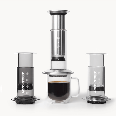 AeroPress coffee maker lineup with a cup of coffee on a white background