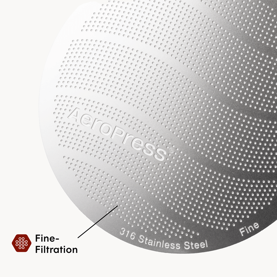 Close-up of an AeroPress coffee maker with 'AeroPress' branding and text indicating 316 stainless steel and fine filtration. #color_pink