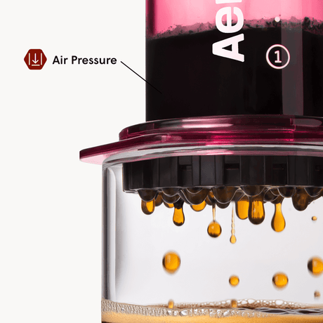 Close-up of a coffee brewing device with air pressure indicator and coffee dripping. #color_pink