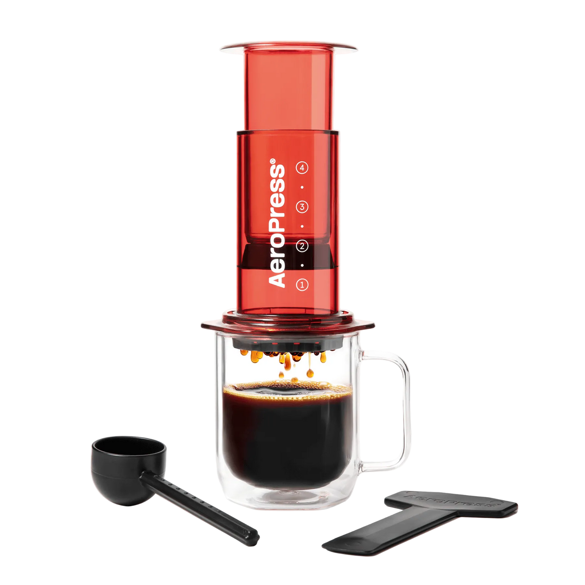 AeroPress coffee maker with a glass mug of coffee and scoop on a white background #color_red