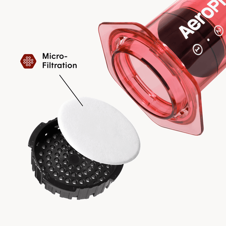 AeroPress coffee maker with a white filter and black valve on a white background #color_red