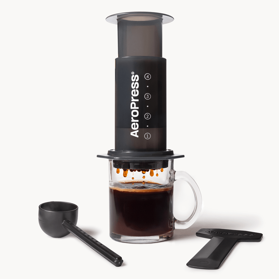 AeroPress Original coffee maker with a glass of brewed coffee on a white background