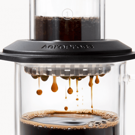 AeroPress Premium coffee maker with coffee being pressed through, showing the brewing process. #color_black
