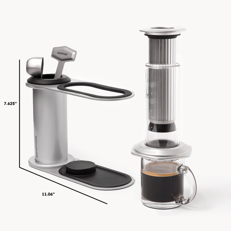 Aeropress coffee maker with a glass mug of coffee on a white background