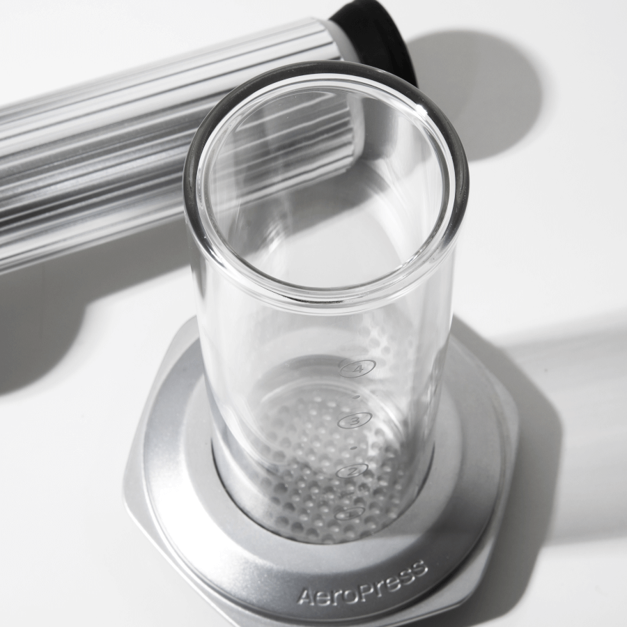 Clear glass AeroPress Premium chamber with metal base on a white surface #color_silver