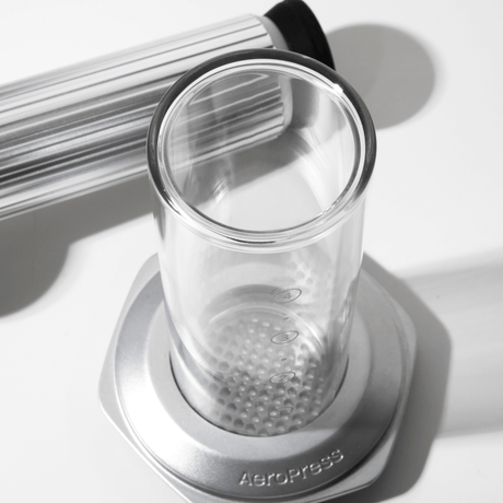 Clear glass AeroPress Premium chamber with metal base on a white surface #color_silver