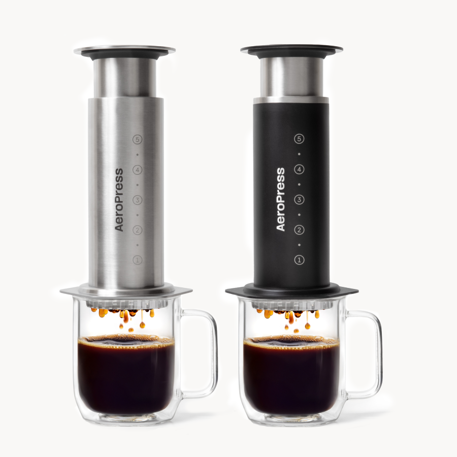 Two AeroPress coffee makers with cups of coffee on a white background #color_silver