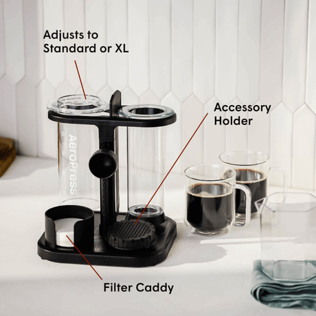 AeroPress coffee maker with accessory holder on a kitchen counter.