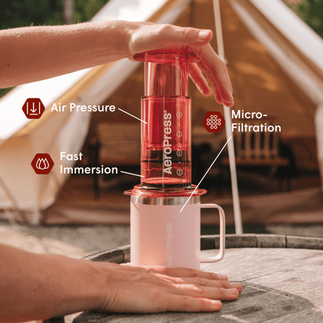 Aeropress coffee maker being used with a tent in the background #color_pink