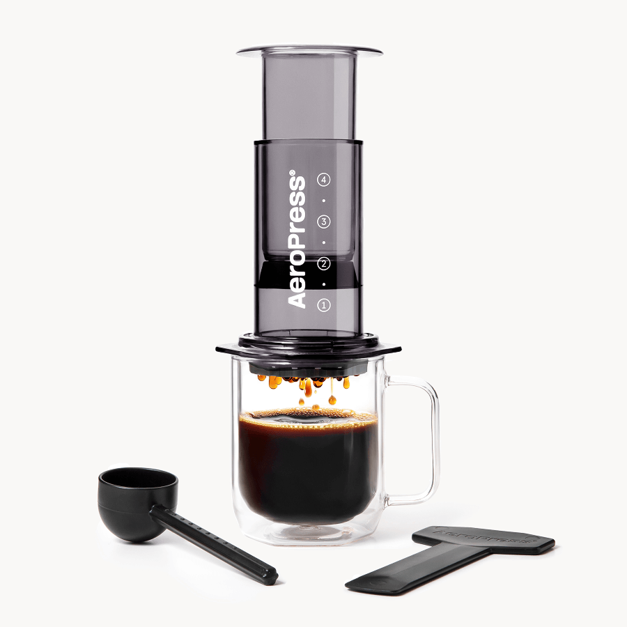 AeroPress coffee maker with a glass mug and scoop on a white background #color_black