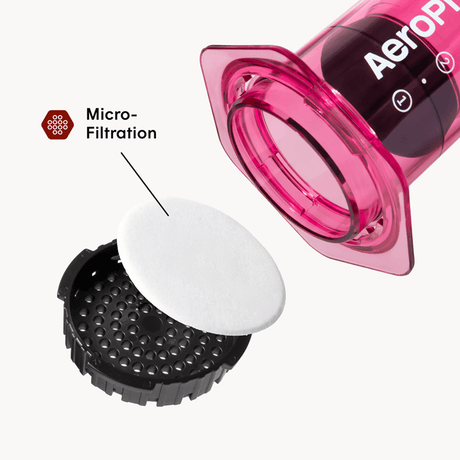 Aeropress coffee maker with a white filter and black valve on a white background #color_pink