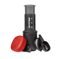 AeroPress Go coffee maker with red lid and black scoop on a white background