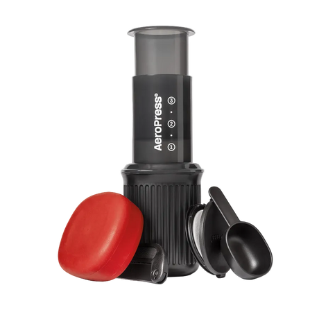 AeroPress Go coffee maker with red lid and black scoop on a white background
