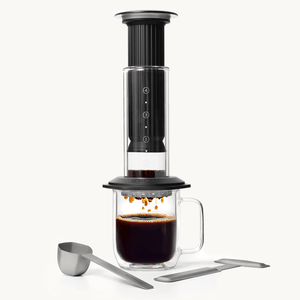 Black AeroPress Premium coffee maker with glass mug on a white background #color_black