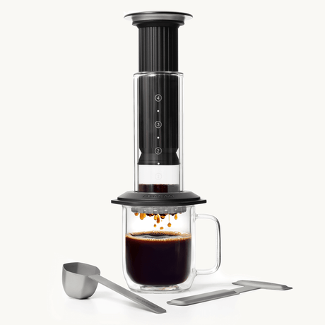 Black AeroPress Premium coffee maker with glass mug on a white background #color_black