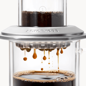 AeroPress Premium coffee maker with coffee being pressed through, showing the brewing process. #color_silver