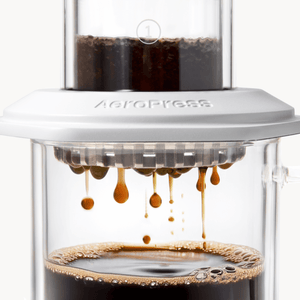 AeroPress Premium coffee maker with coffee being brewed, showing the process of making coffee. #color_white