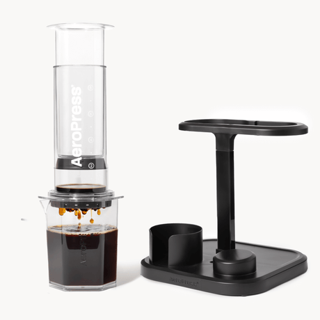 AeroPress coffee maker with a black stand on a white background